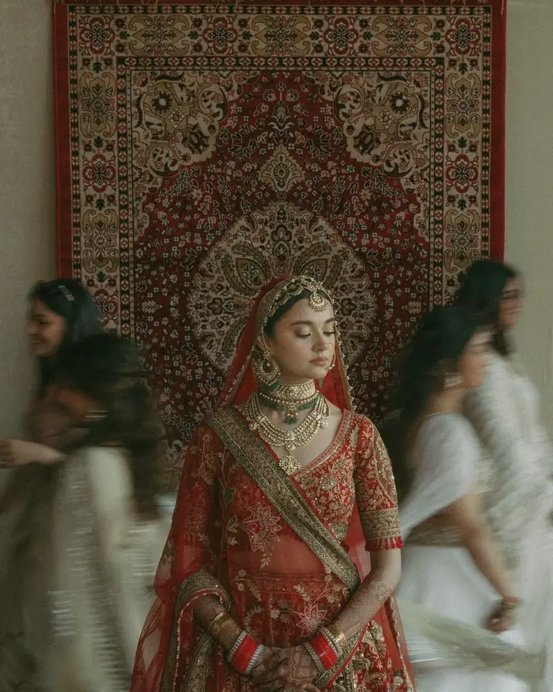 A bride seated calmly while her friends move around her in a blur