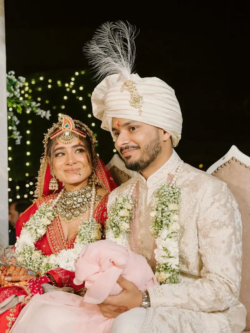The bride and groom smiling side by side, wearing their varmala garlands