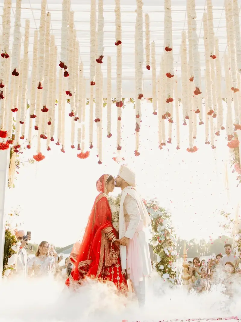 The couple embracing under hanging white flowers as low smoke rolls across the floor