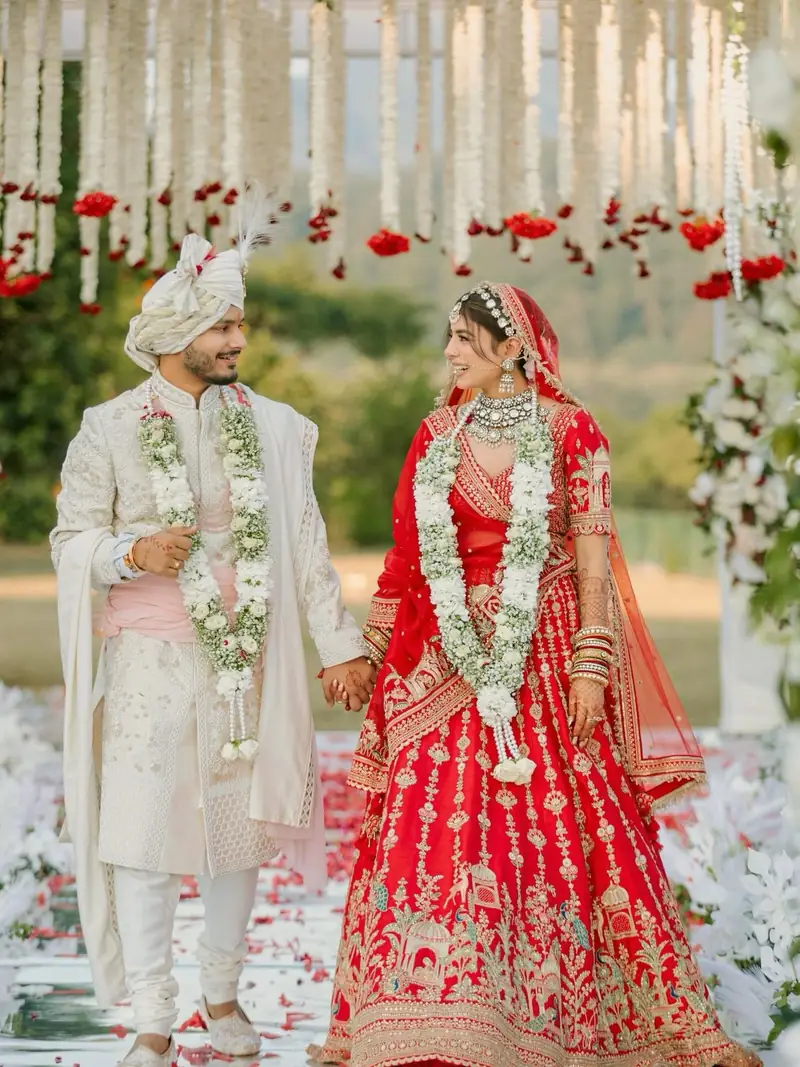 The couple walking hand in hand down an aisle of rose petals