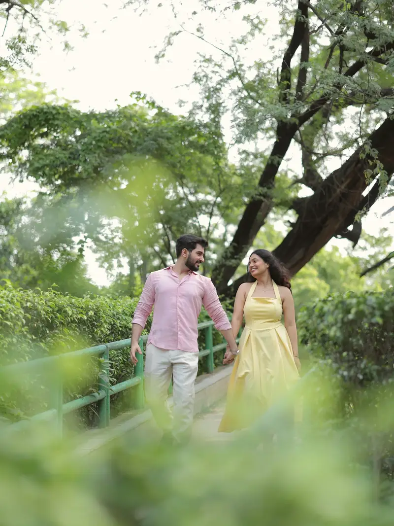 The couple walking on a garden path, framed by out-of-focus leaves