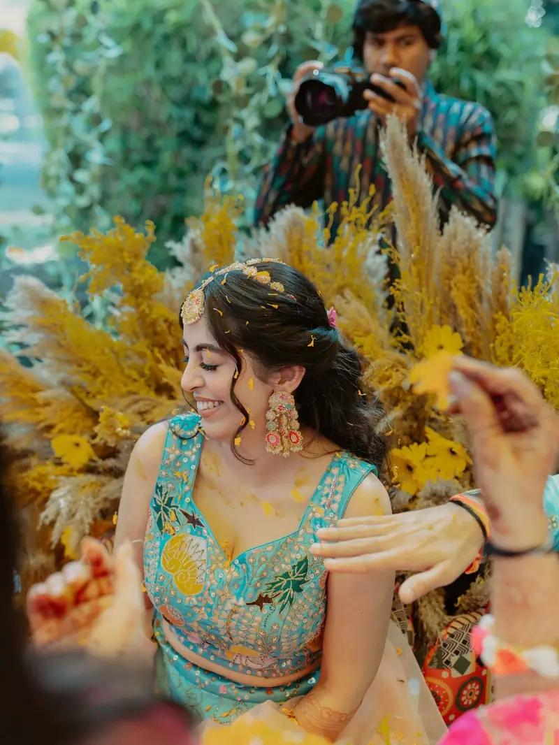 The bride in a turquoise blouse laughing as petals fall around her