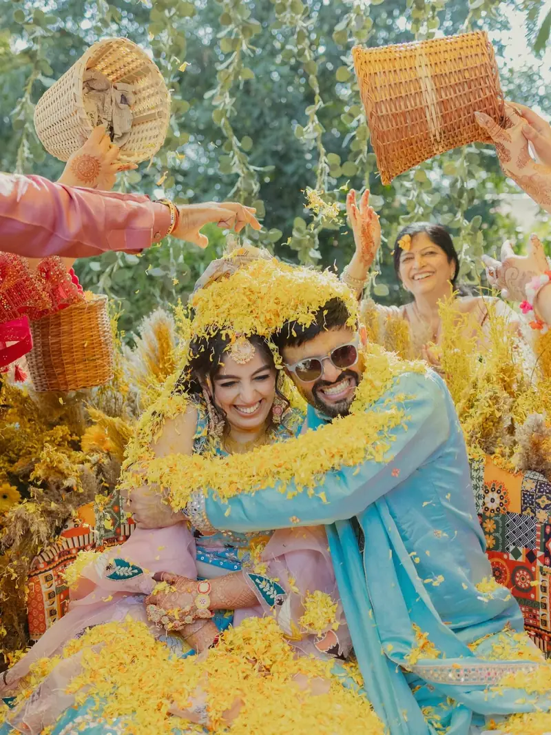 Family showering the laughing couple with yellow flower petals from wicker baskets