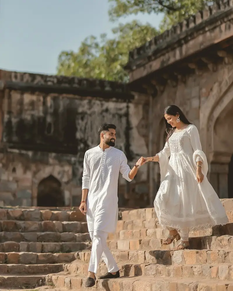A couple in white walking down the worn stone steps of an old monument