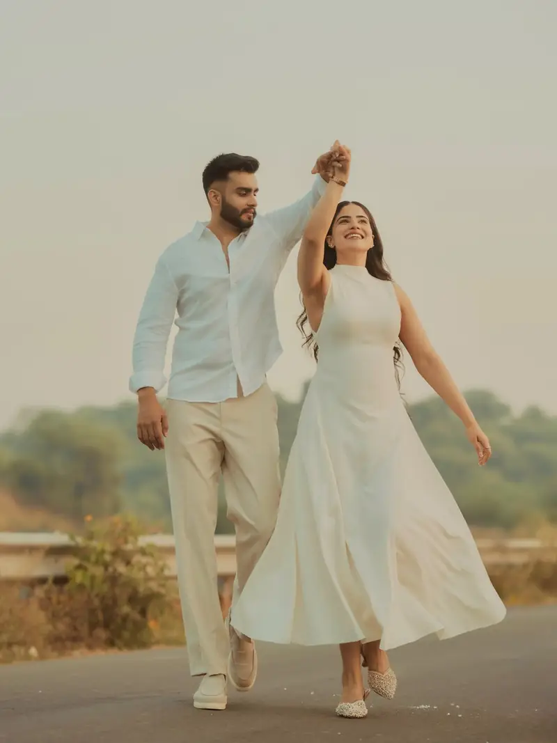 A woman in a white dress twirling under her partner's arm on an empty road