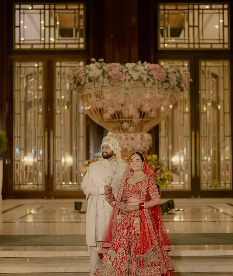 The couple embracing in front of lit glass doors at night