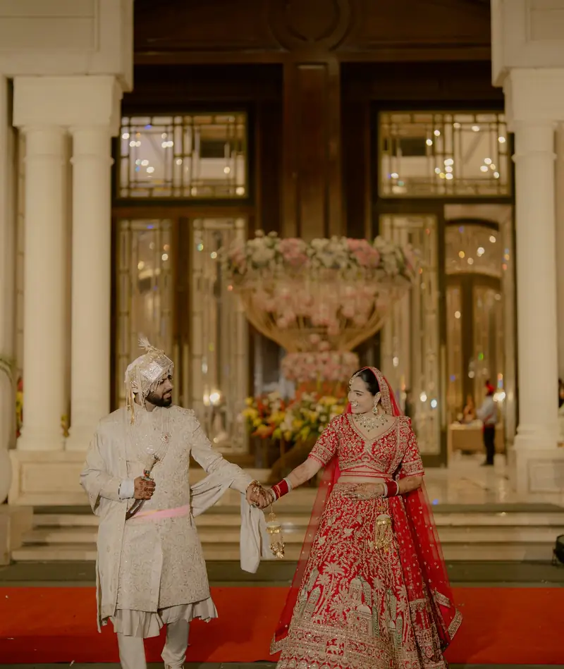 The couple walking down a red carpet in front of the venue's glass doors