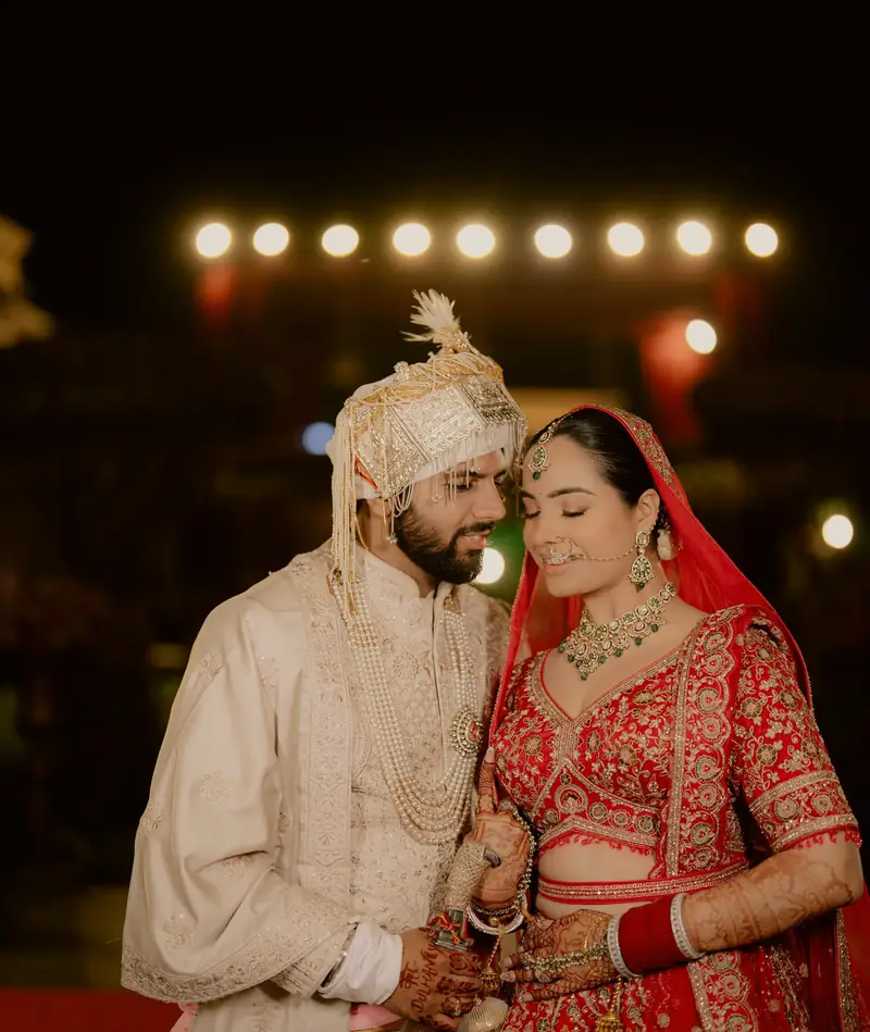 The couple holding each other under a row of warm lights, his kirpan at his side