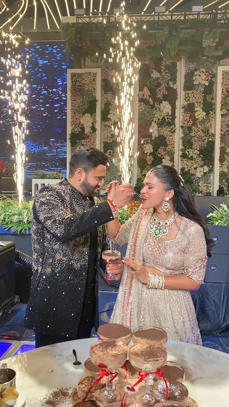 The groom feeding the bride dessert as sparkler fountains go off behind them