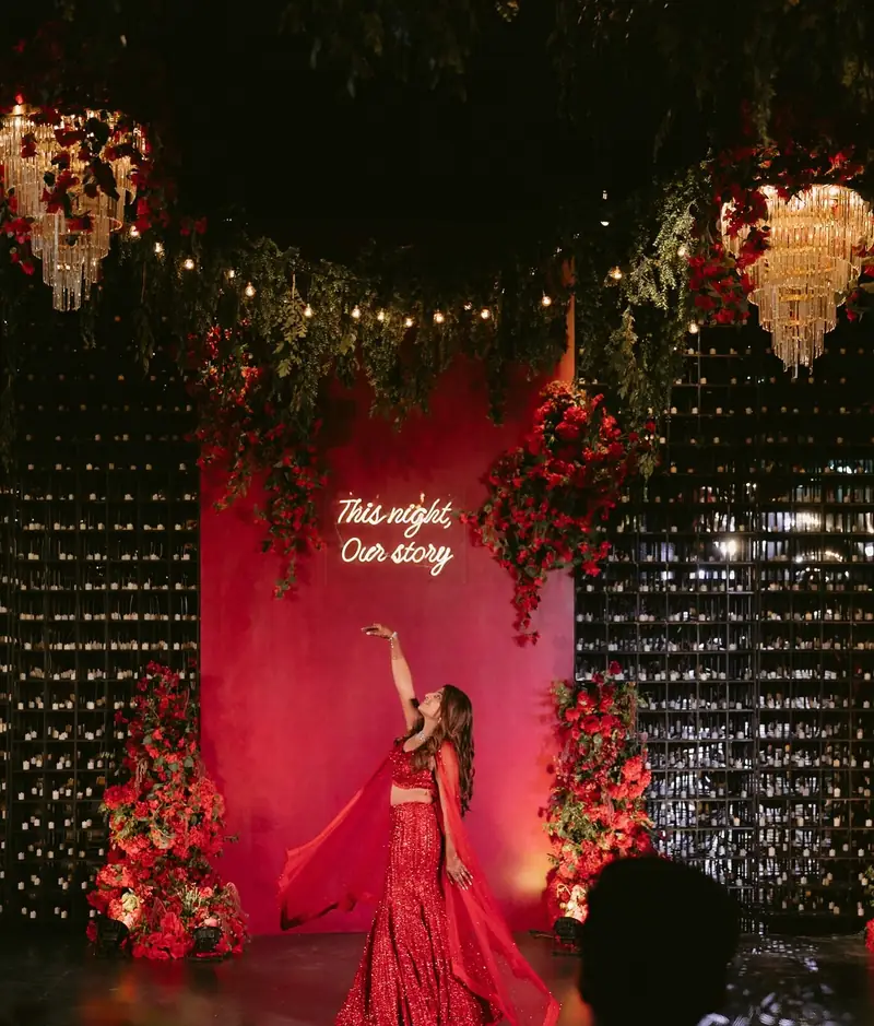 The bride dancing on stage with one arm raised, framed by red roses