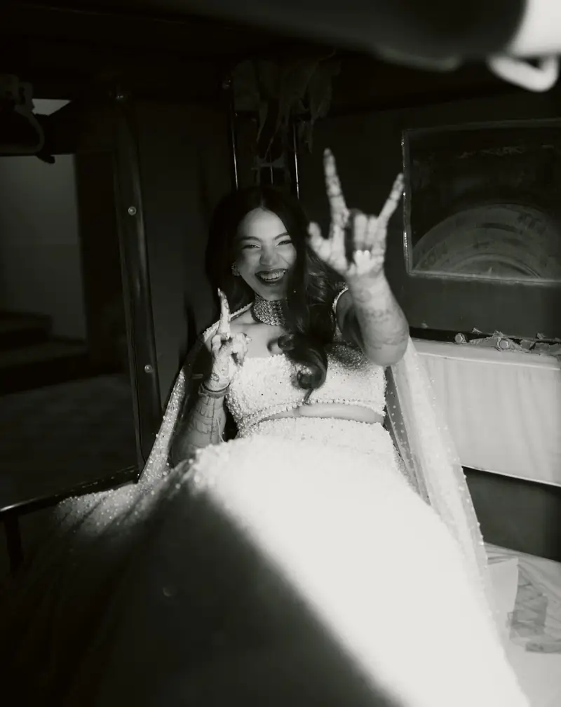 Black and white photo of the bride laughing and throwing a rock-on sign
