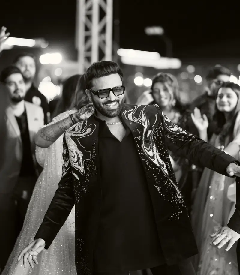 Black and white photo of the groom dancing in a crowd of friends