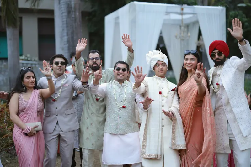 The groom and his family cheering with their hands in the air during the baraat