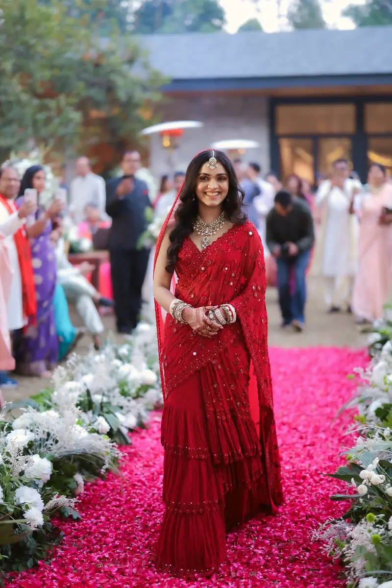 The bride walking down an aisle of pink rose petals, guests following behind