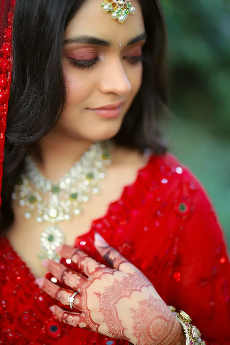 Close-up of the bride looking down at her mehendi, wearing a kundan necklace