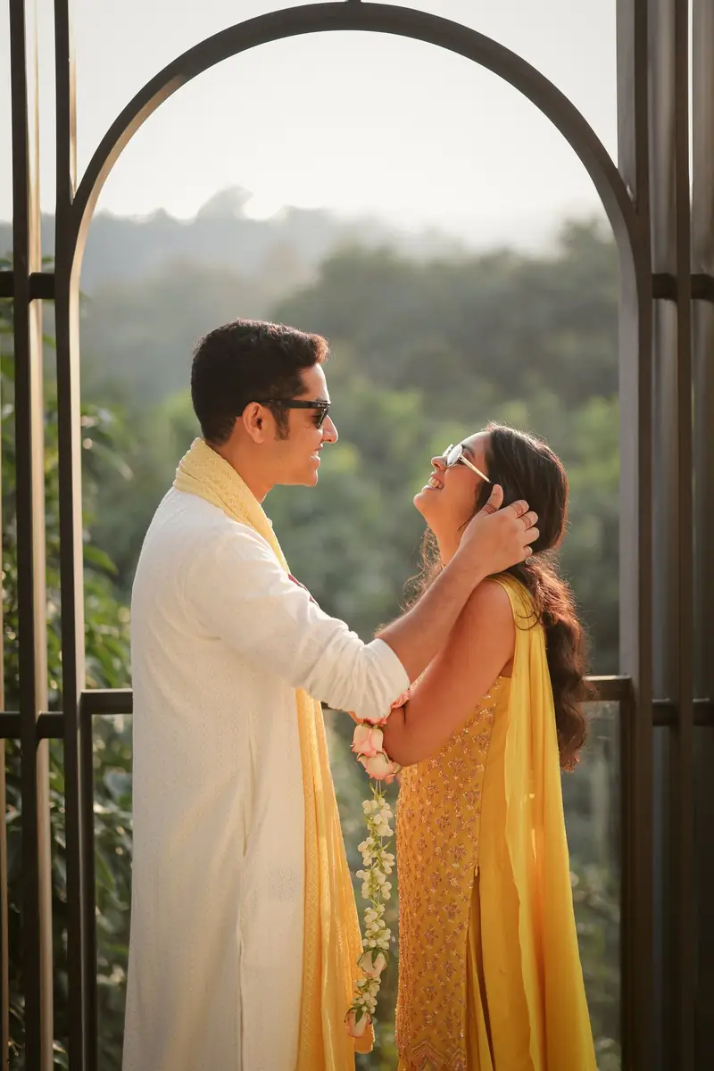 The groom tucking the bride's hair behind her ear inside a metal arch, hills in the distance